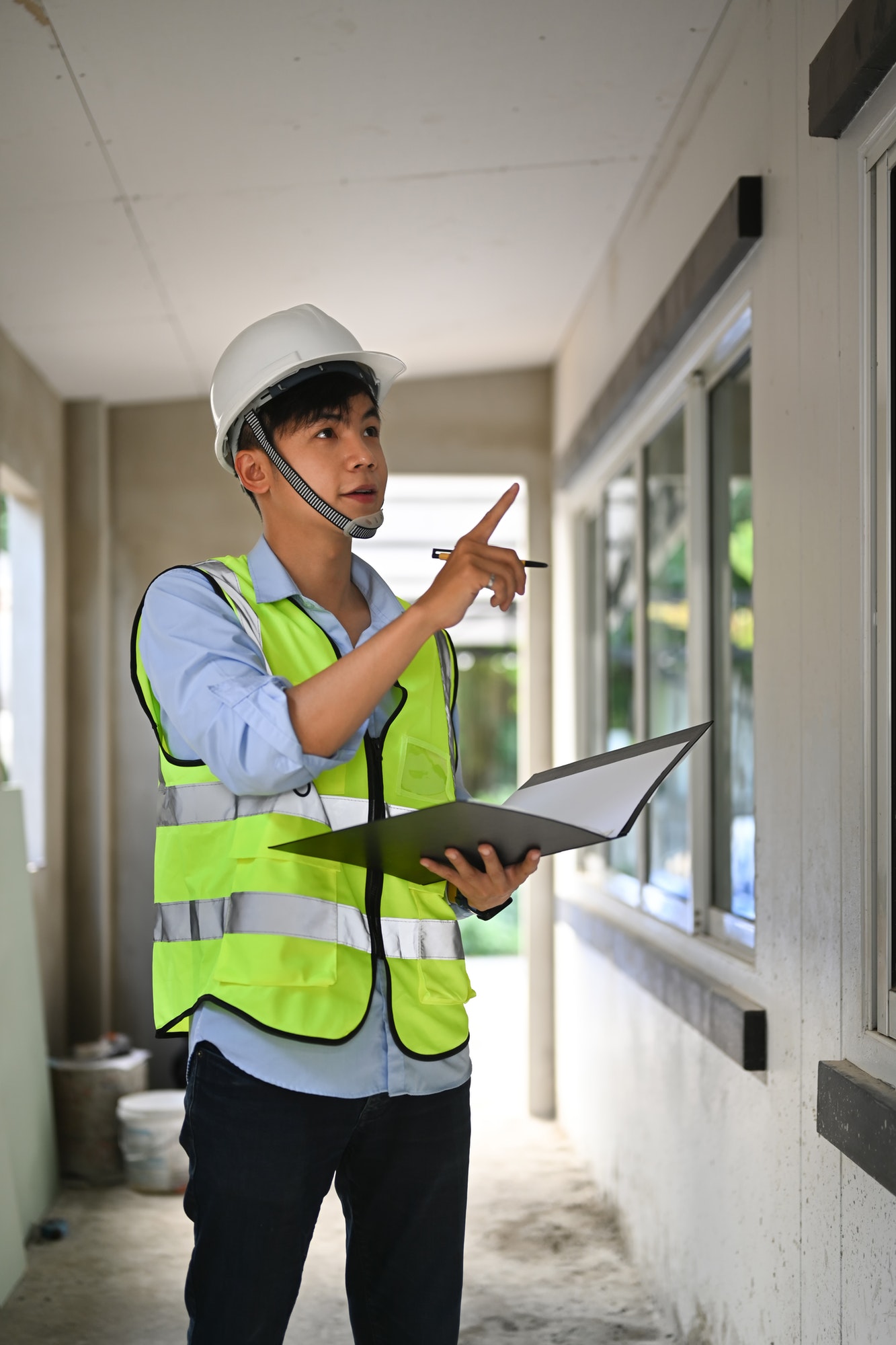 Asian man inspector holding document, inspecting the reconstructed construction.