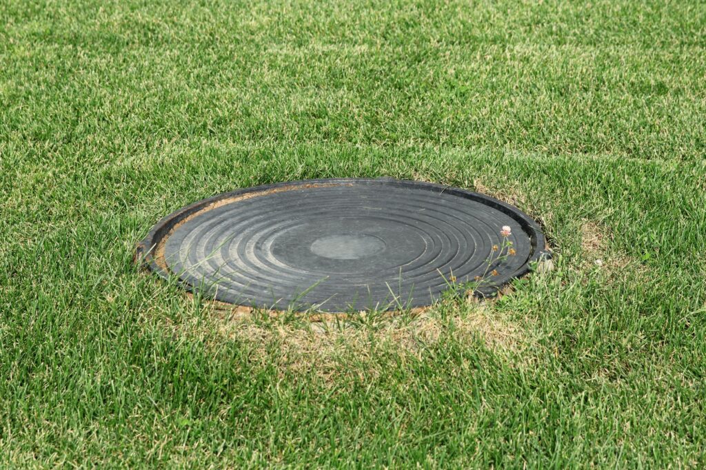 Metal manhole in a background of green grass on the field
