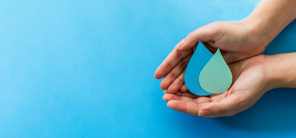 woman hands holding paper cut water drops on a blue background - clean water and sanitation